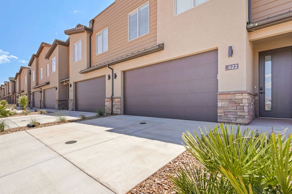 a sidewalk in front of a house with a garage door