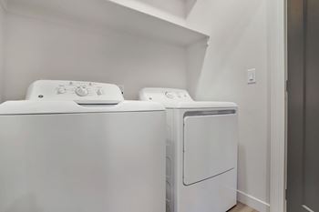 Two white front loading washing machines in a laundry room.