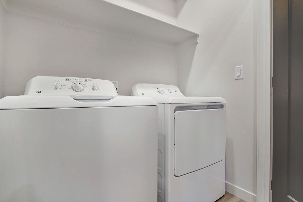 Two white front loading washing machines in a laundry room.