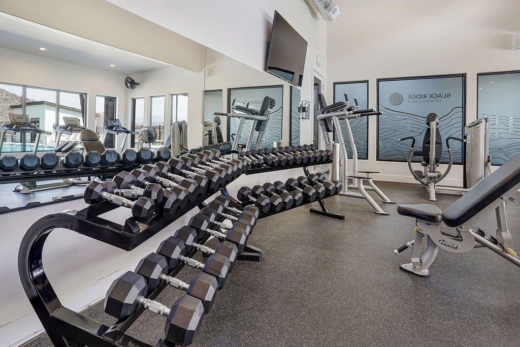 A gym with a row of dumbbells and weight machines.