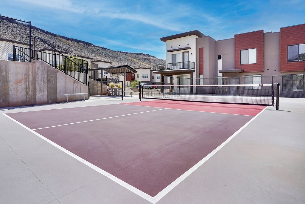 Tennis court in front of a building with a black fence.