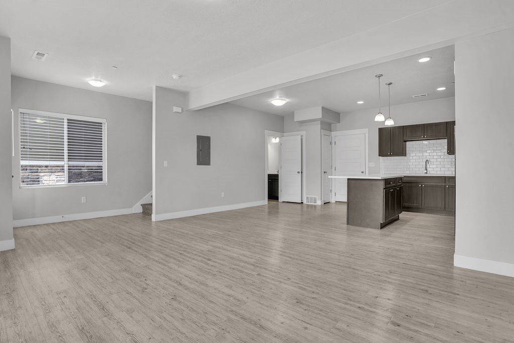 A spacious living room with a kitchen in the background.