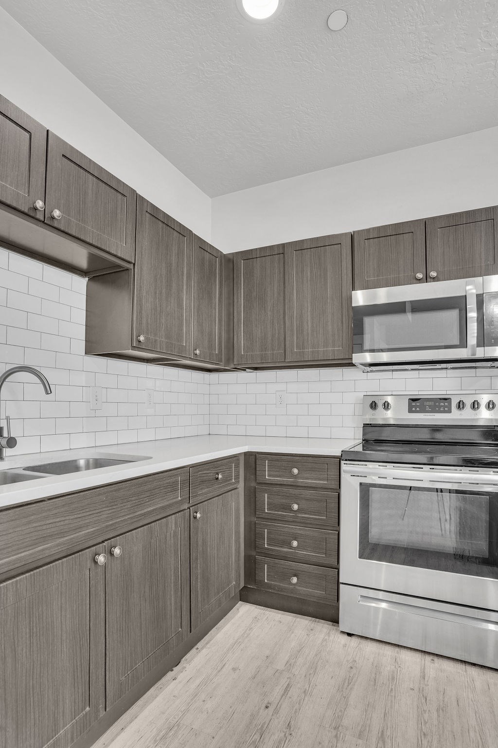 A kitchen with a stove, sink, and cabinets.