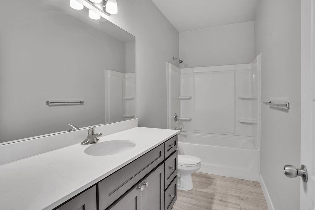A white bathroom with a sink, mirror, and toilet.