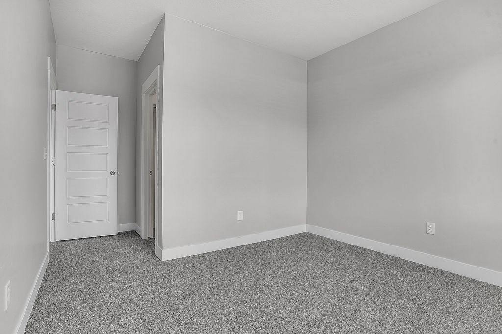 A room with a carpeted floor and a white door.