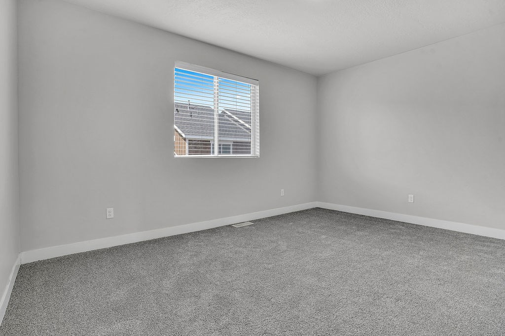 A room with a window showing a view of a house and a utility pole.