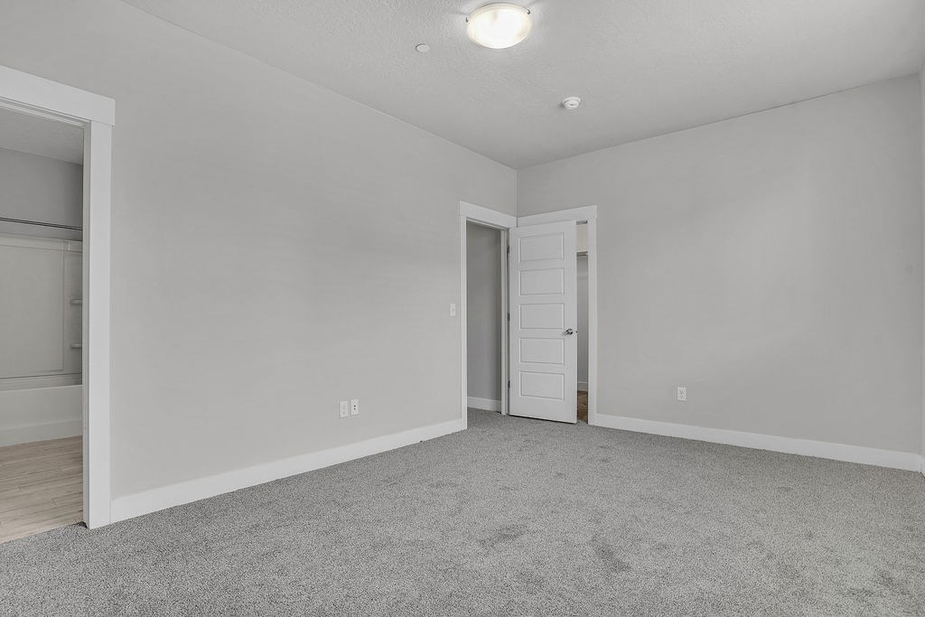 A room with a carpeted floor and two doors.