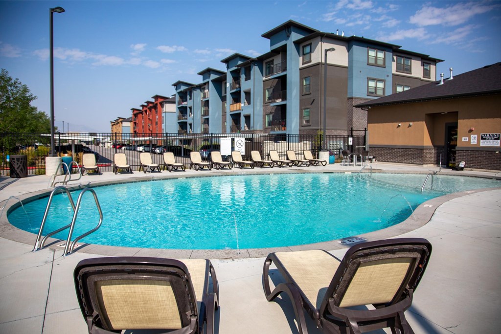 Two chairs are placed on the side of a swimming pool.