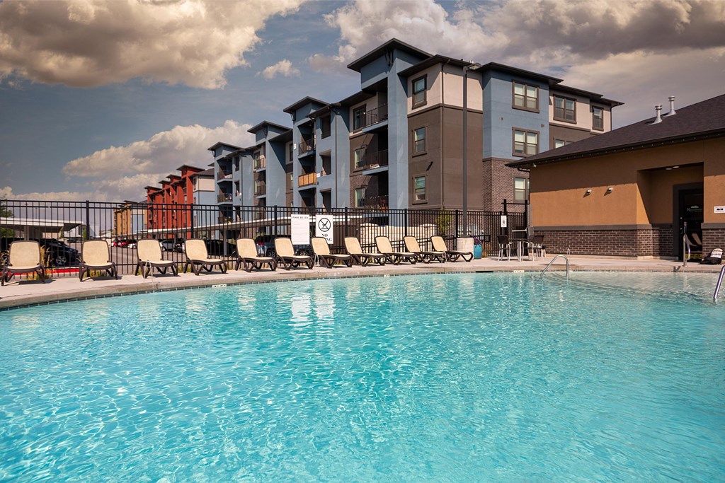 A swimming pool in front of a multi-story apartment building.