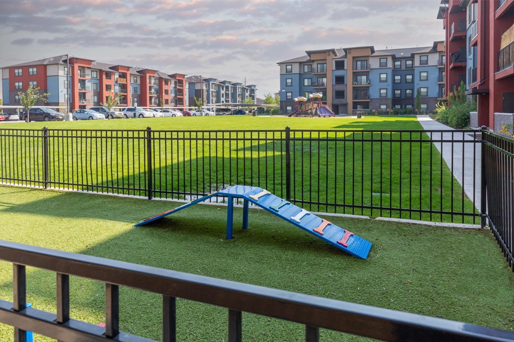 A playground with a blue slide in the foreground and apartment buildings in the background.