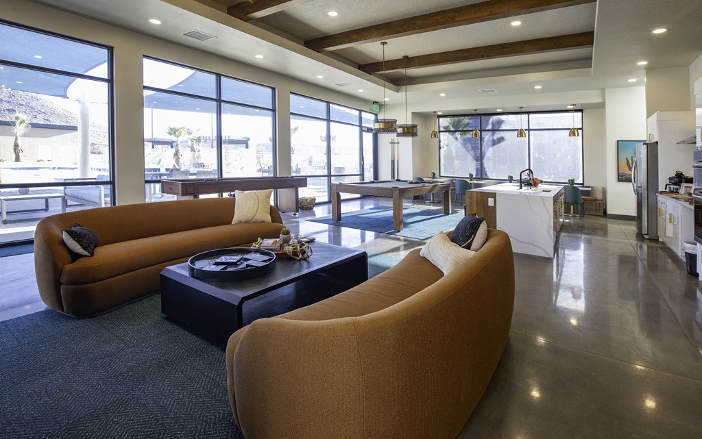 a living room with brown couches and a table and windows