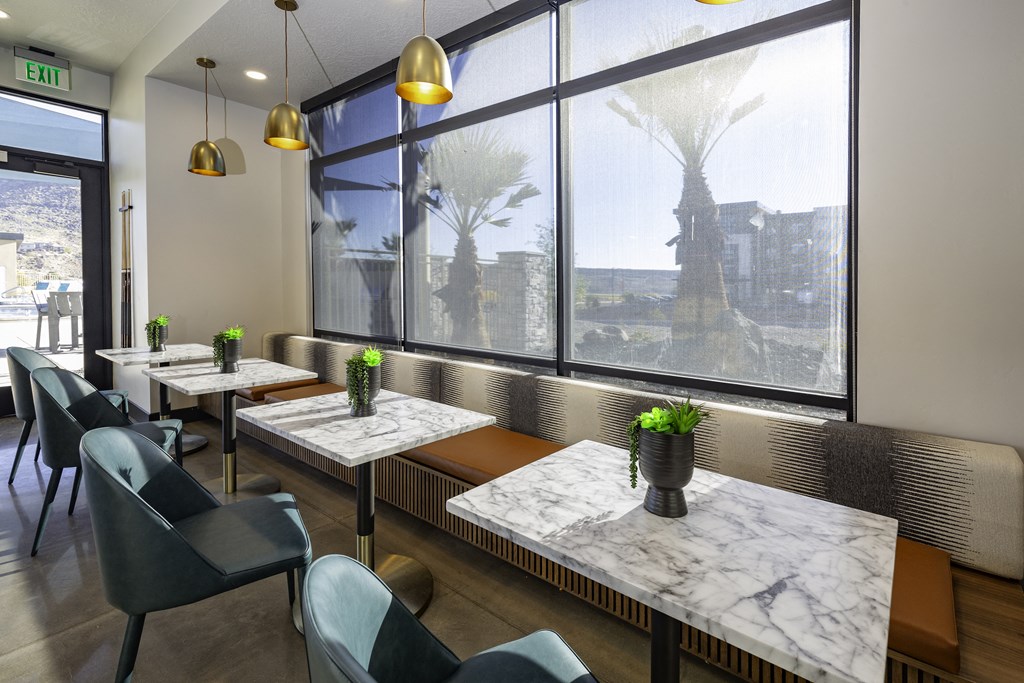a bistro area with marble tables and chairs and a large window