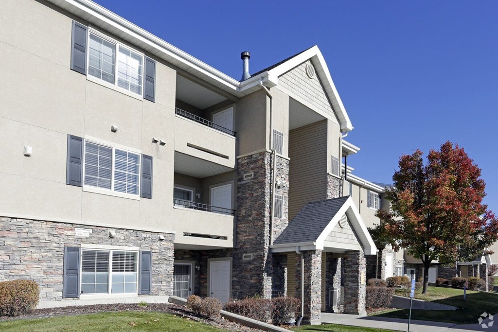 an exterior view of an apartment building with a lawn and trees