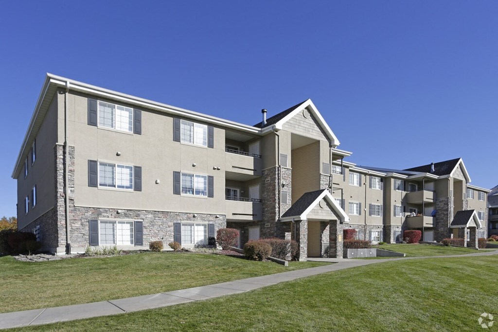 an exterior view of an apartment building with green grass and a sidewalk