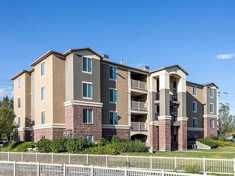 A large apartment building with a white picket fence in front.