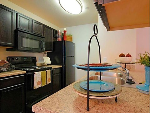 A kitchen with black cabinets and a black stove top oven.