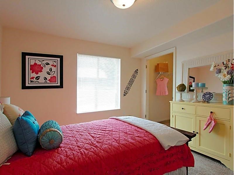 A bedroom with a red bedspread and a yellow dresser.