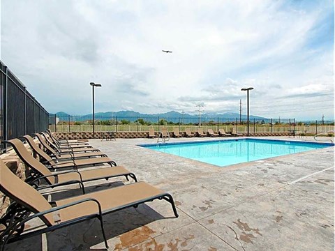 A pool surrounded by chairs and a fence.