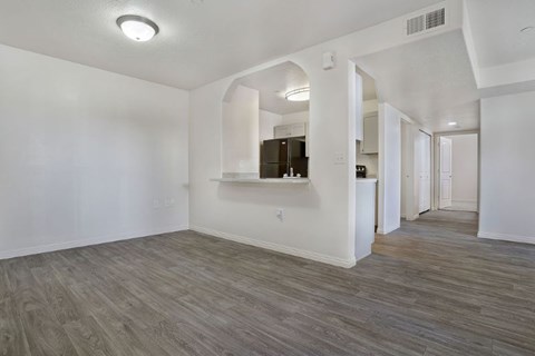 A spacious room with wood flooring and white walls.