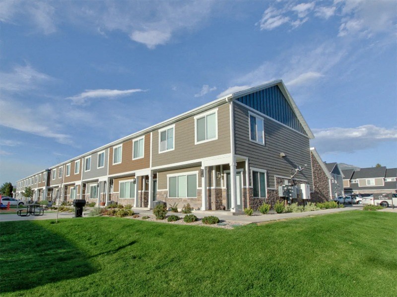 a row of houses with a green lawn and a blue sky