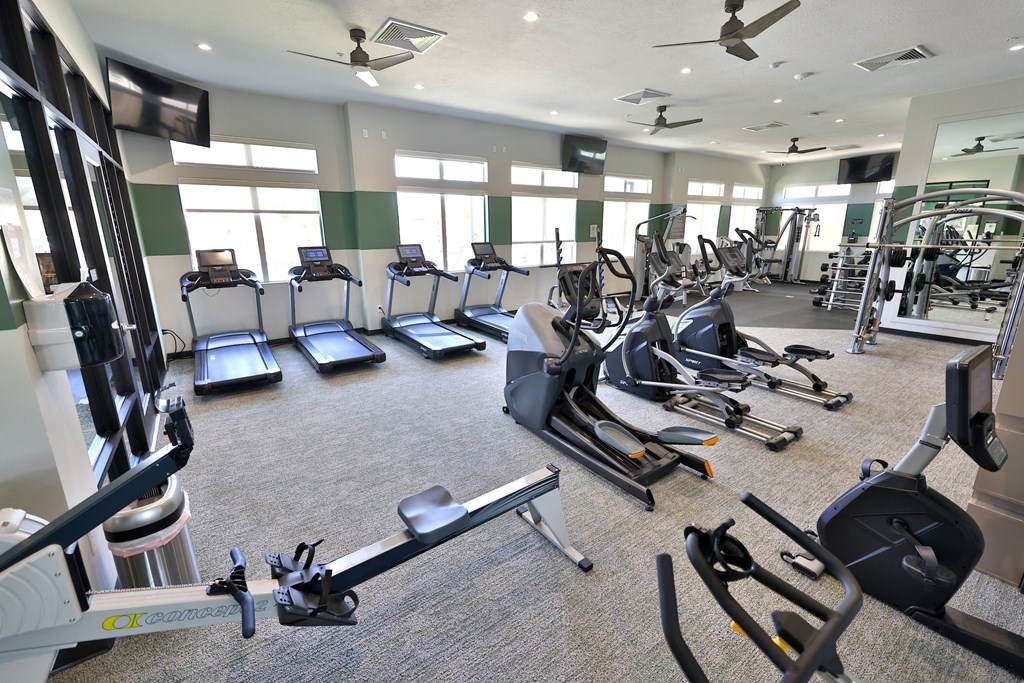a gym with cardio equipment and windows in a building