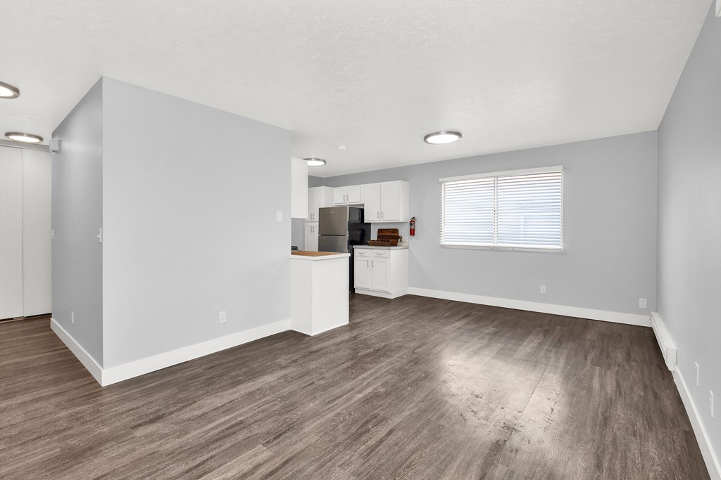 A spacious room with wooden flooring and white walls.