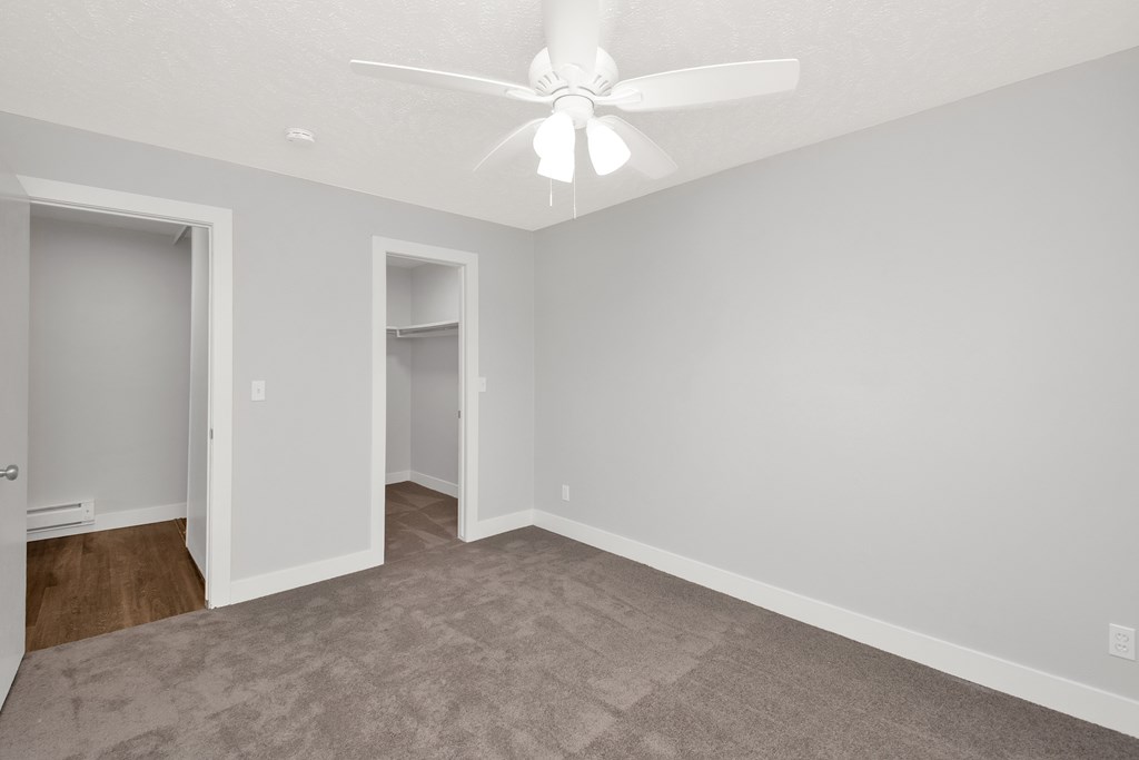 A room with a ceiling fan and carpeted floor.