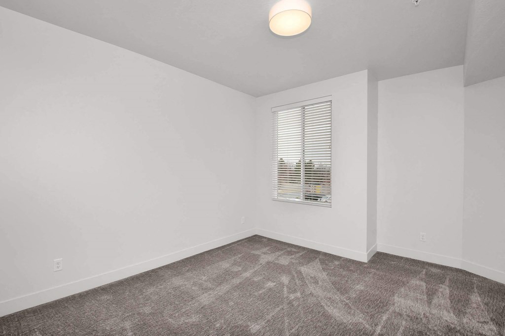 a bedroom with white walls and a window