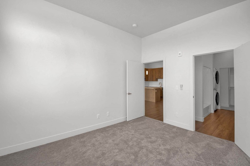 a bedroom with a medium sized bed and a doorway into a kitchen