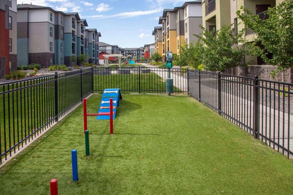 a grassy area with benches and a fence in front of an apartment complex