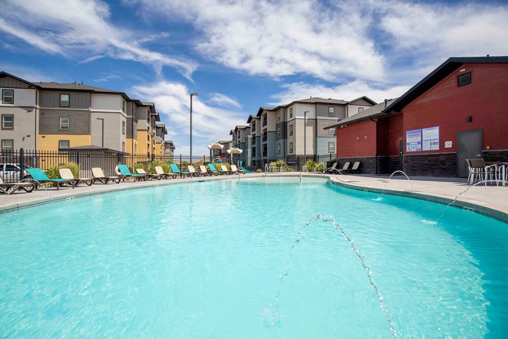 pool with lounge chairs and apartment buildings in the background