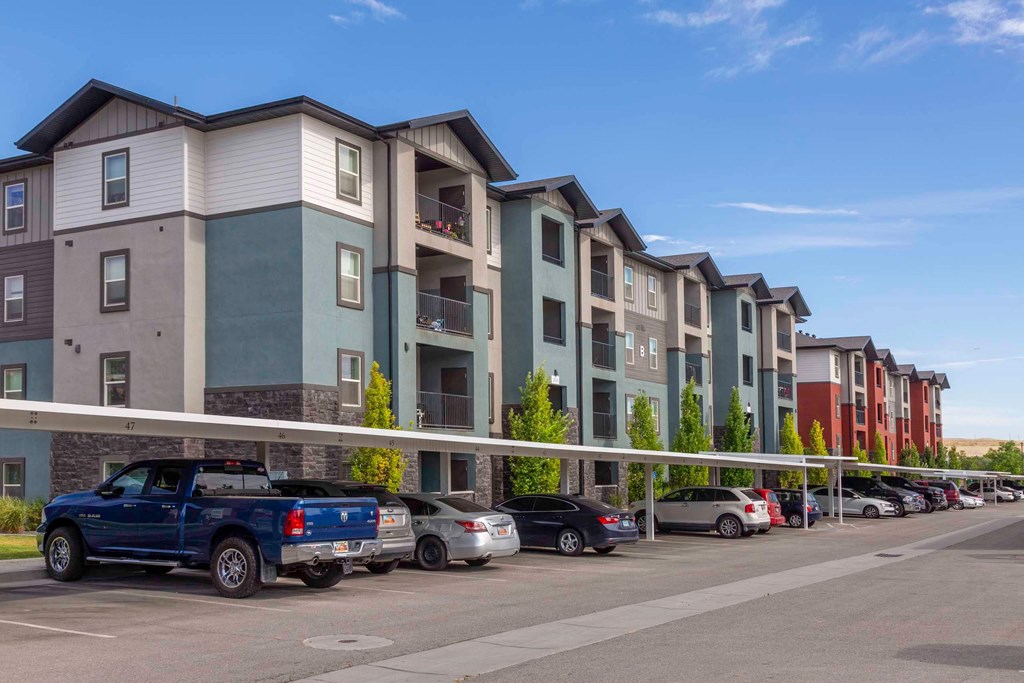 a row of apartment buildings with cars parked in front of them