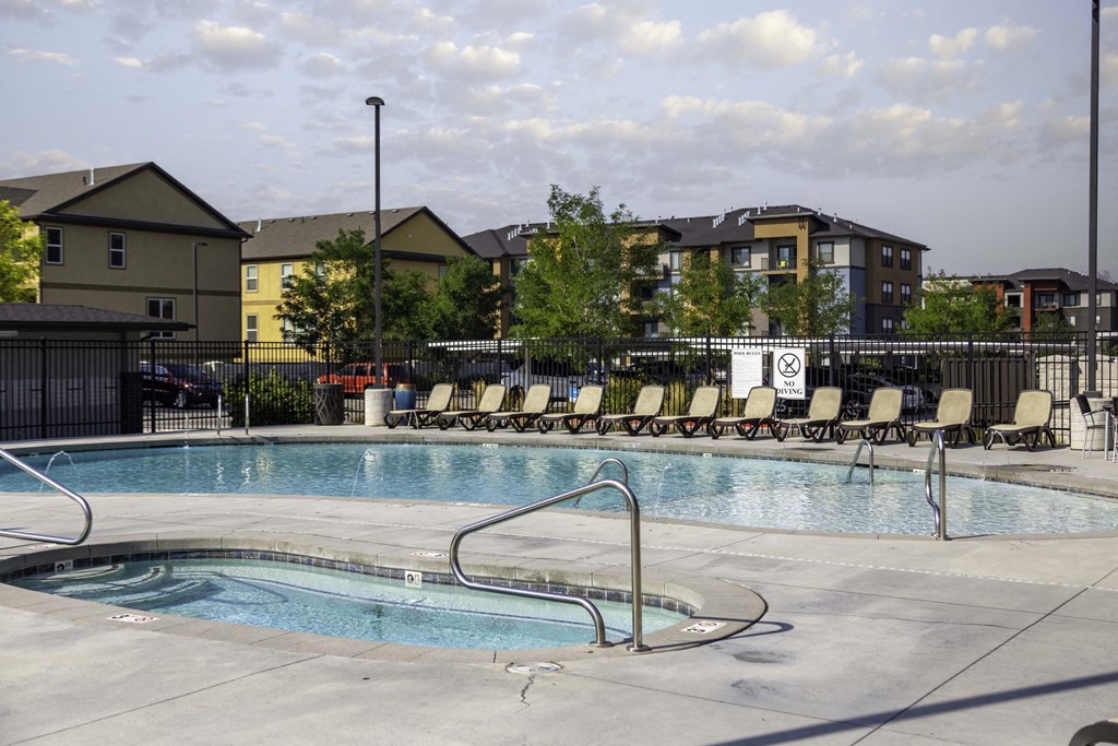 a swimming pool with chaise lounge chairs and buildings in the background