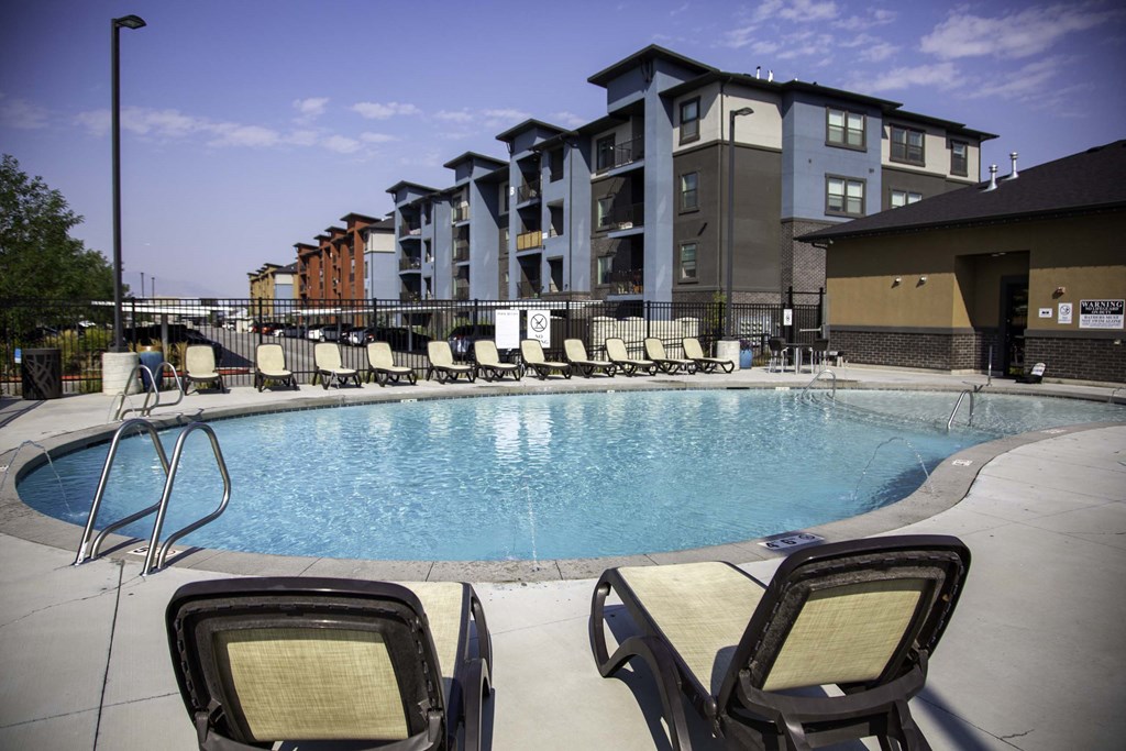 an outdoor pool with lounge chairs and a building in the background