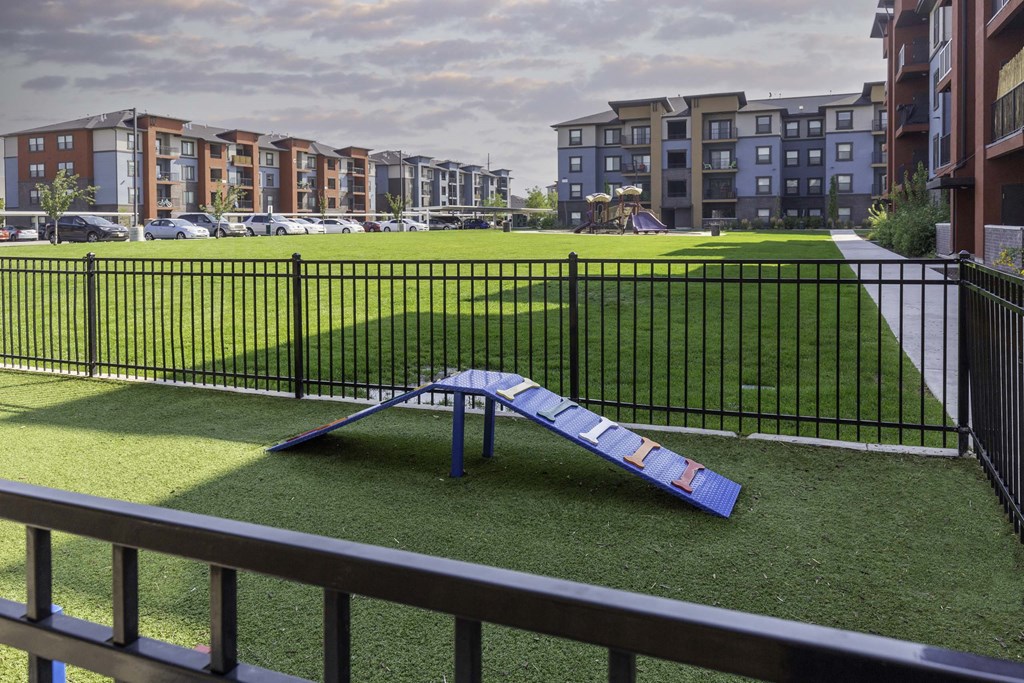 a blue slide sits in the middle of a grassy area in front of an apartment complex