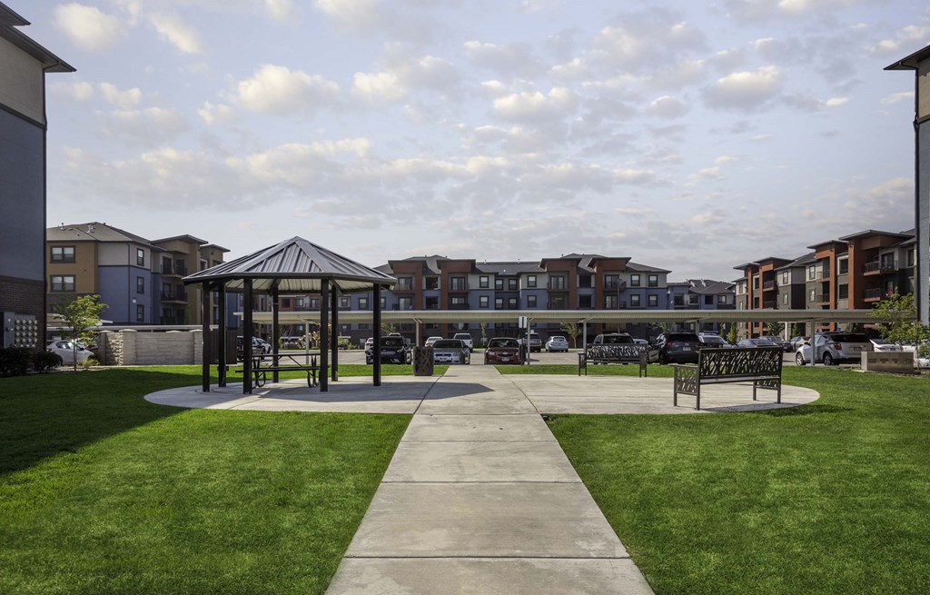 a gazebo sits in the middle of a grassy area with a bench