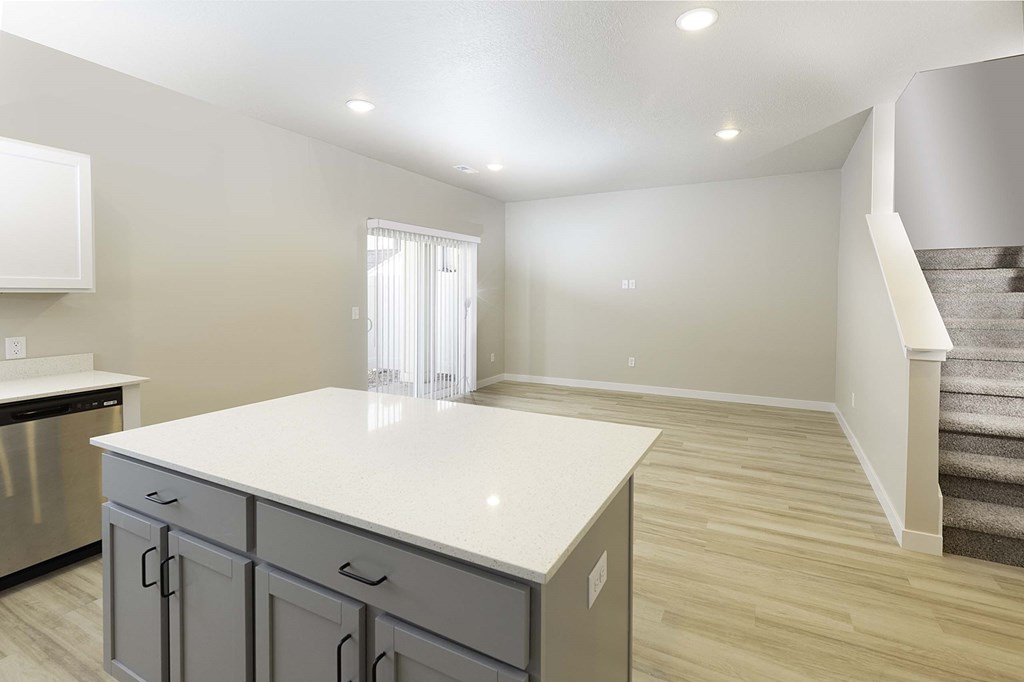 a kitchen and living room with a staircase in the background