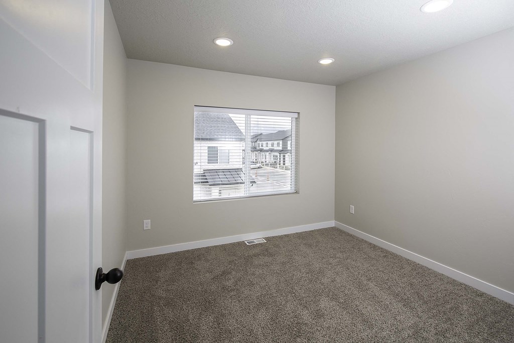 a bedroom with a large window and carpeted flooring