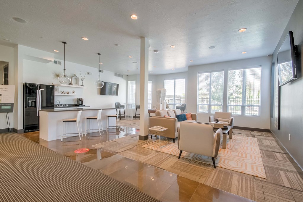 a living room with couches and chairs and a kitchen with a refrigerator and microwave