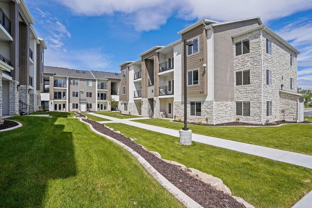 an exterior view of an apartment building with green grass and sidewalks