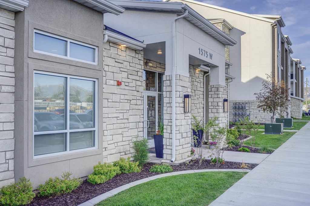 the front of a building with a sidewalk and grass