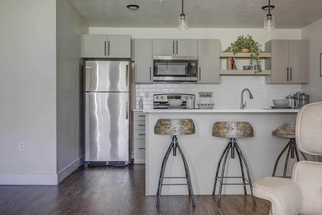 a kitchen with bar stools and a refrigerator