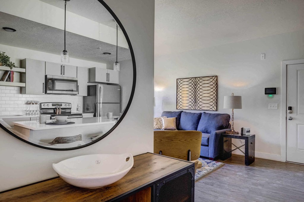 a kitchen and living room with a sink and a mirror