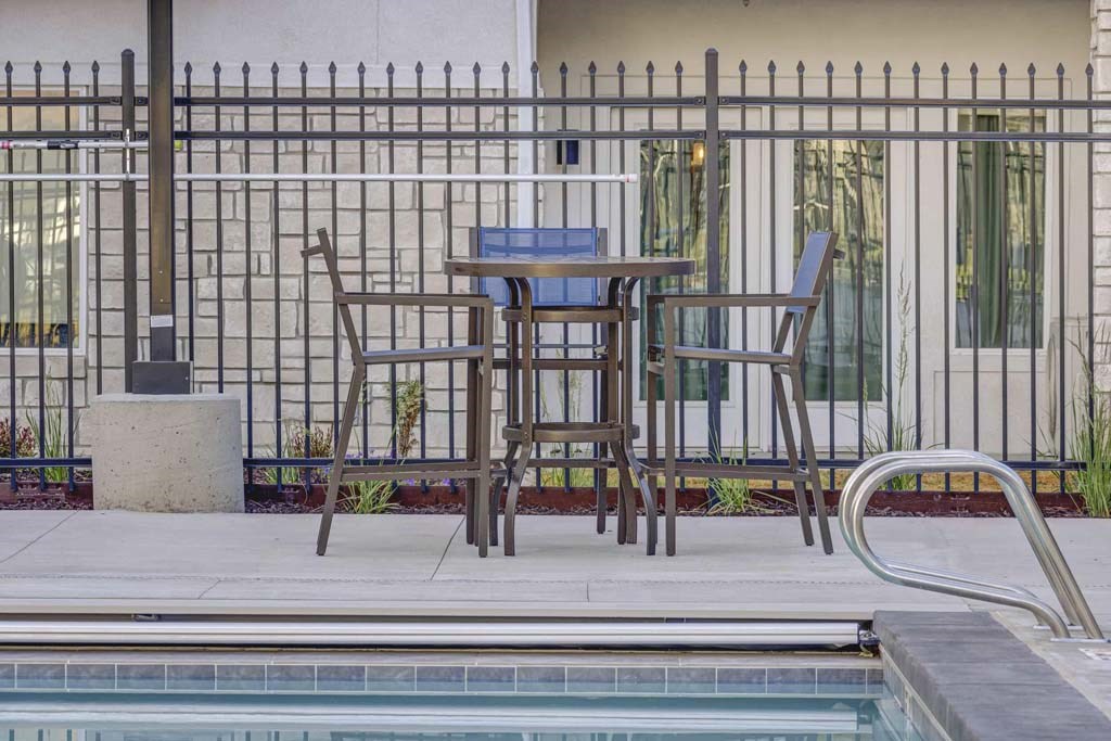 A poolside table with two chairs is set up next to a pool.