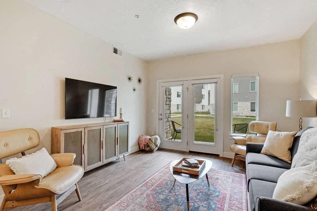 A living room with a wooden chair, a sofa, a coffee table, and a television.