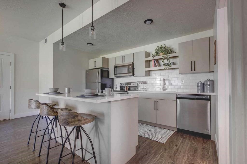 A kitchen with a white counter and bar stools.