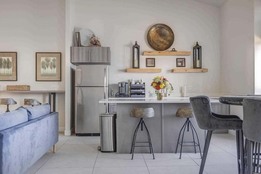 A modern kitchen with a blue sofa and a grey chair.