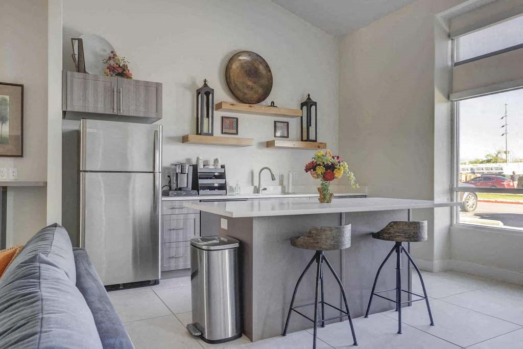 A modern kitchen with a refrigerator, stove, and bar stools.