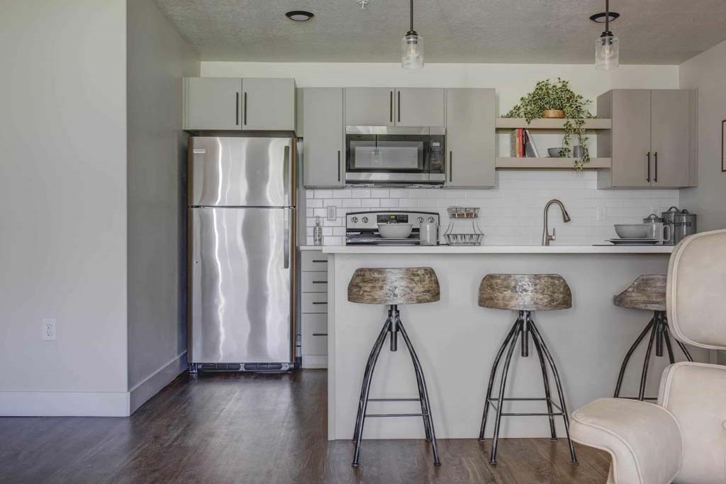 A kitchen with a white counter and bar stools.