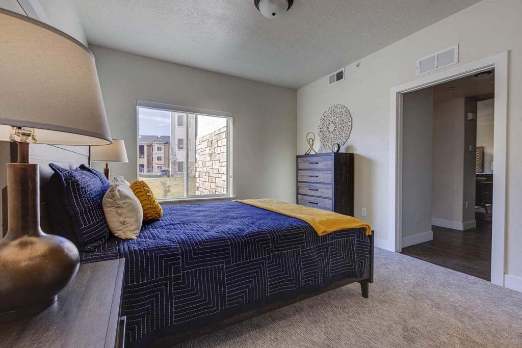 A bedroom with a bed, nightstand, and lamp.